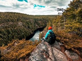 man sitting on a rock overlooking a pristine valley with a river and trees 