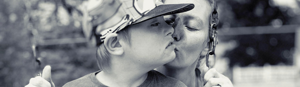 photo of mother pushing boy on swing