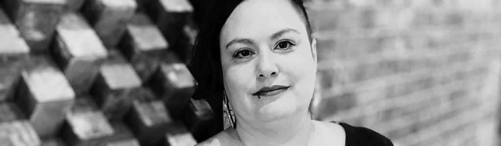 photo of woman standing against a quilt on a brick wall